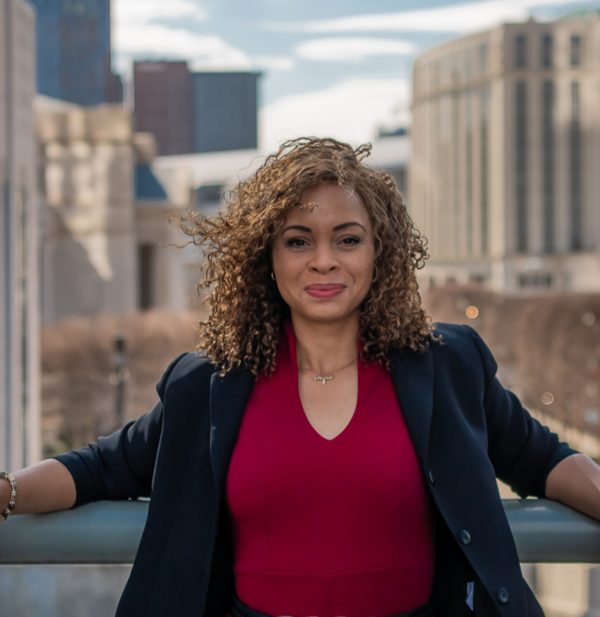Portia Cue, actor and voice over artist, in a red top and dark blazer against the city skyline